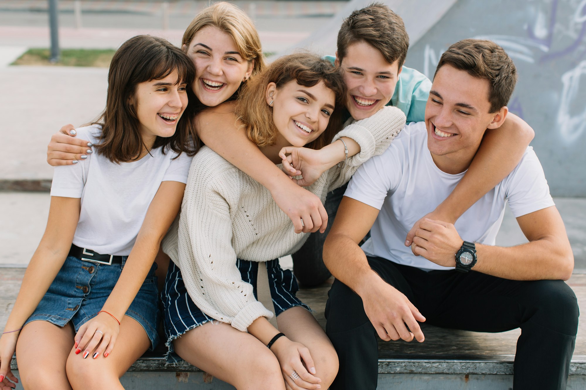 Summer holidays and teenage concept - group of smiling teenagers hanging out outside.